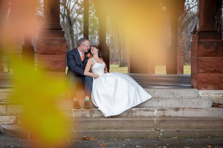 A man and woman sitting on steps in front of trees.