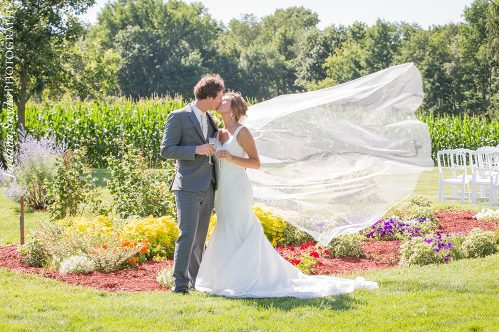 A bride and groom kissing in the grass.