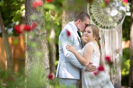 A man and woman hugging in front of trees.