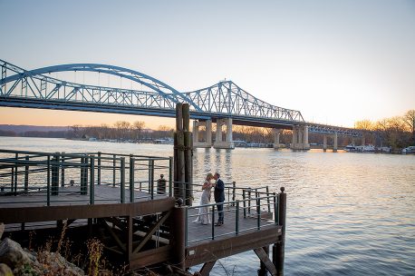 A couple standing on the pier near the water.