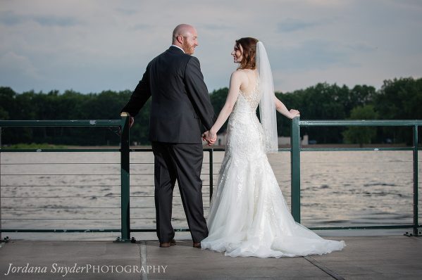 A man and woman holding hands on the side of a pier.