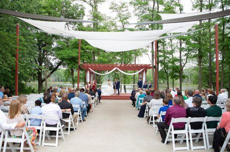 A wedding ceremony with many people sitting in chairs.