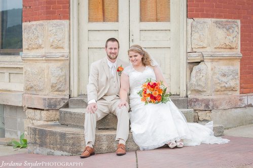 A bride and groom pose for a picture outside of the church.