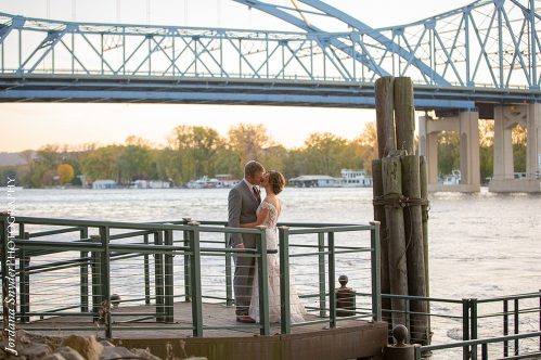 A couple is standing on the dock of a pier.