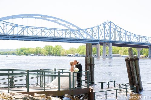 A bride and groom kissing on the pier.