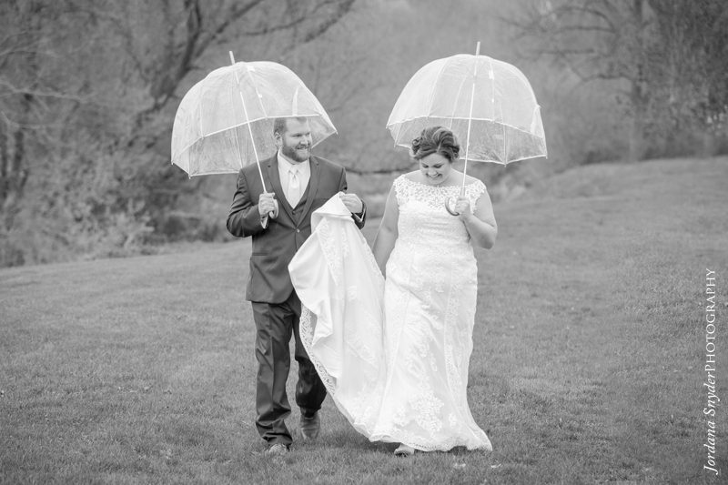 A man and woman walking in the rain holding umbrellas.