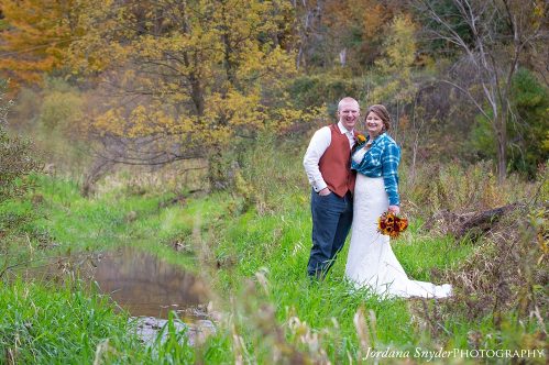 A man and woman standing in the grass near water.