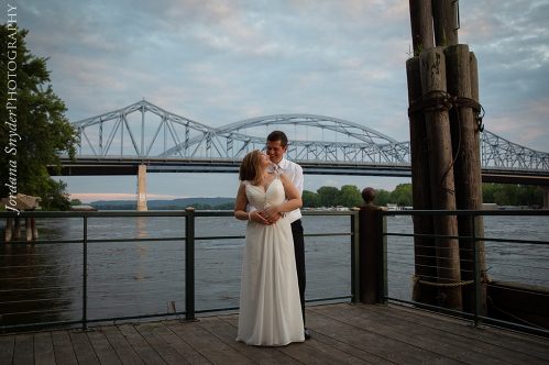 A man and woman kissing on the pier.