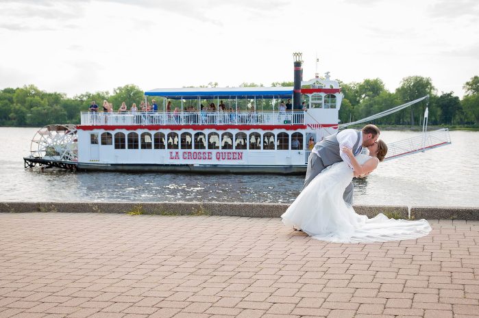 A bride and groom kissing in front of a boat.