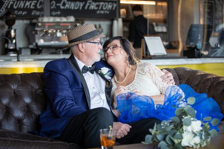 A man and woman sitting on top of a brown couch.