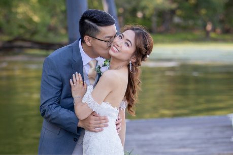 A man and woman kissing in front of a body of water.