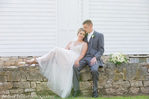 A man and woman sitting on the side of a wall.