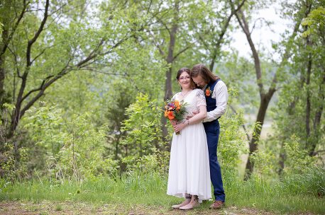 Two people standing in a field with trees