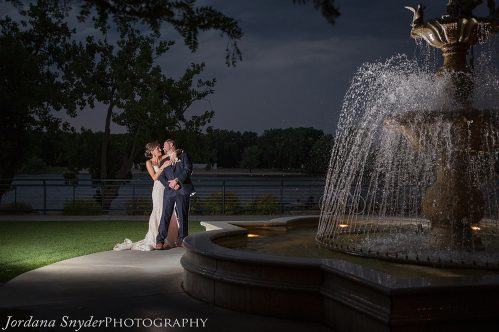 A couple is standing in front of a fountain