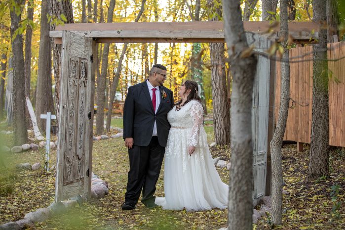 A man and woman standing in front of trees.