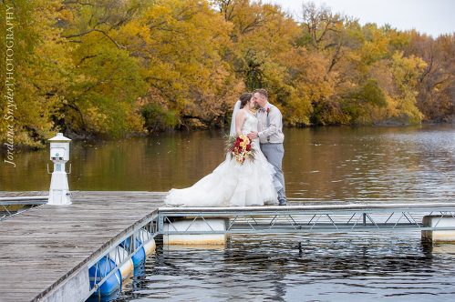 A bride and groom kissing on the dock
