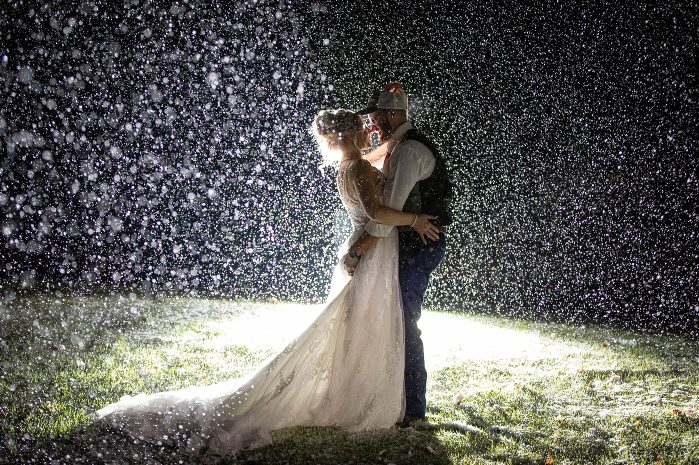 A bride and groom kissing in the rain.