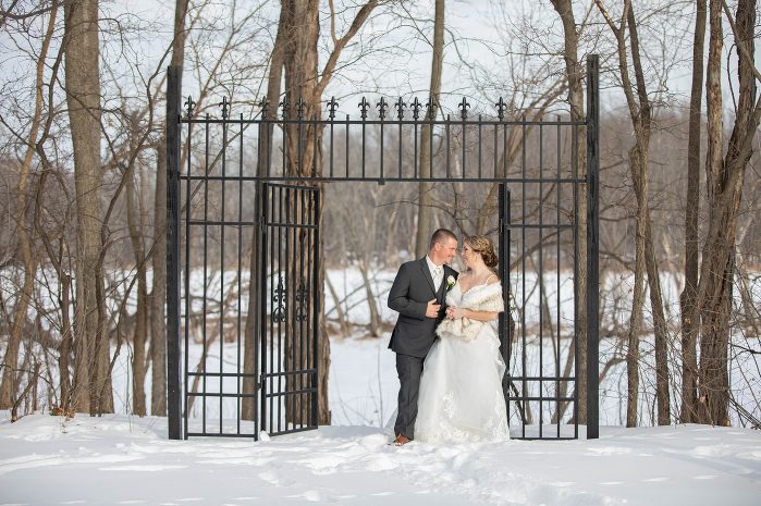 A man and woman kissing in front of a black iron gate.