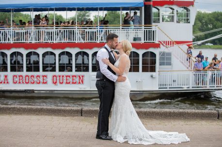 A bride and groom kiss in front of the boat.