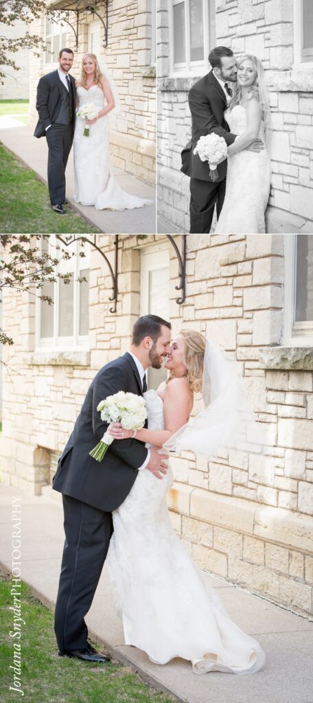 A bride and groom kissing in front of a stone building.