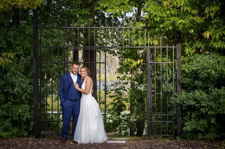 A man and woman posing for a picture in front of an iron gate.