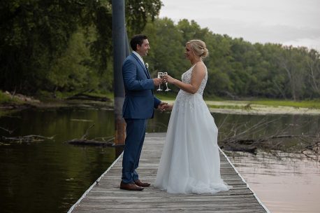 A man and woman standing on the dock of a lake.