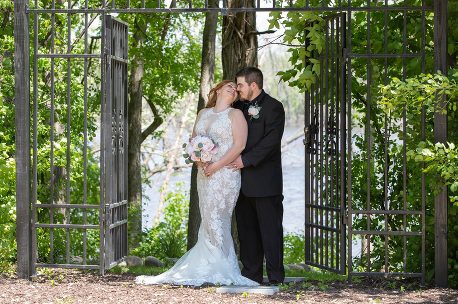 A bride and groom pose for a picture in the woods.