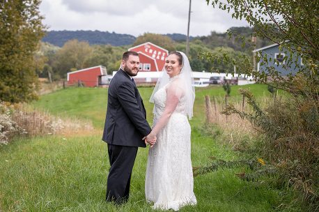 A newly married couple holding hands in the grass.