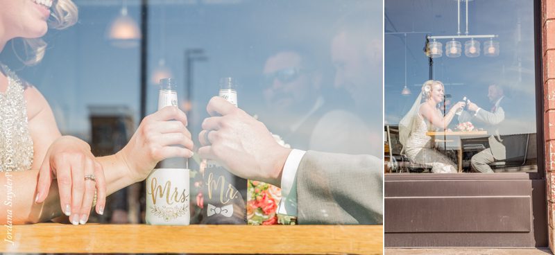 A man holding two bottles of wine in front of a window.