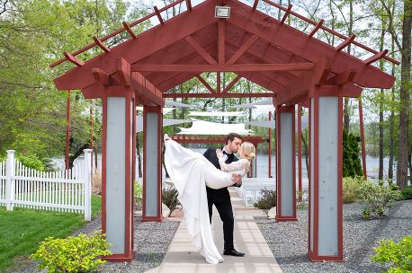 A man and woman kissing under an arbor.