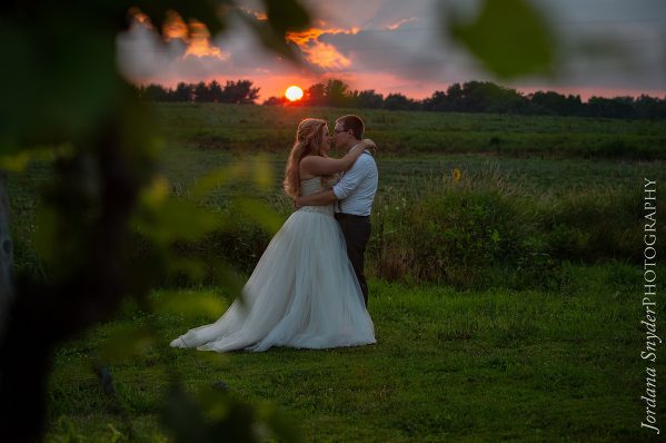 A bride and groom kissing in the sunset.