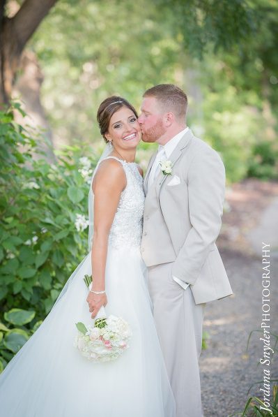 A bride and groom kissing on the side of a road.