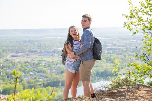 A man and woman standing on top of a hill.