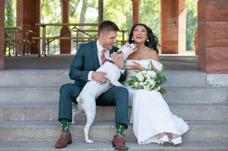 A man and woman sitting on steps with their dog.