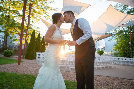 A bride and groom kissing under an umbrella.