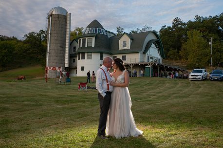 A man and woman standing in front of a barn.