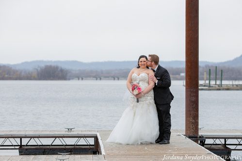 A bride and groom kissing on the pier.