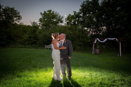 A bride and groom kissing in the grass.