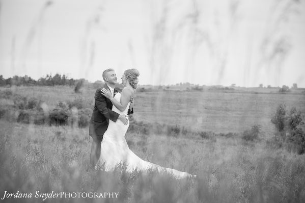 A black and white photo of a bride and groom in the grass.