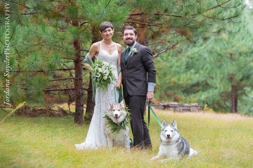 A bride and groom pose with their dogs.