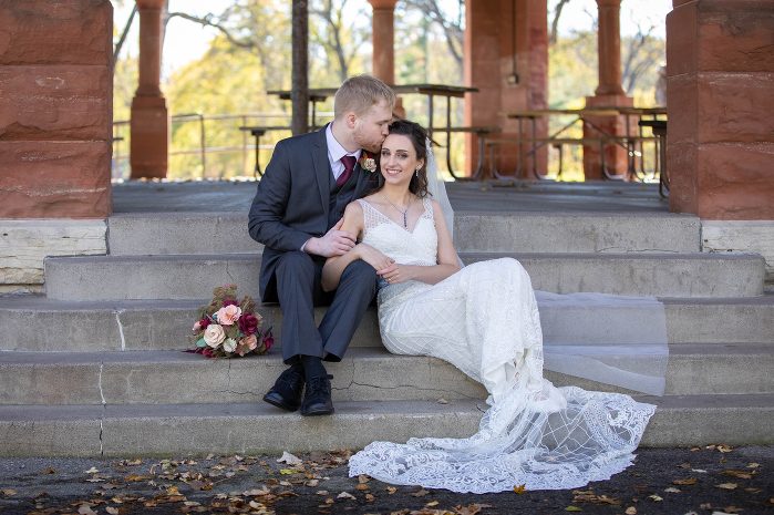 A man and woman sitting on steps in front of a gazebo.