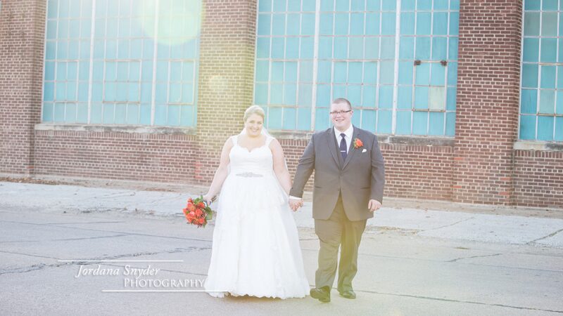 A man and woman holding hands in front of a building.