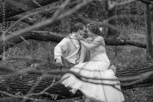 A man and woman kissing in front of some trees.
