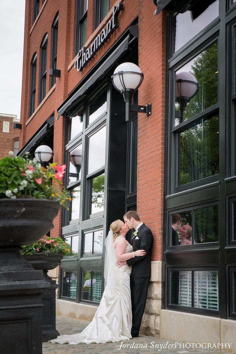 A bride and groom kissing in front of a building.