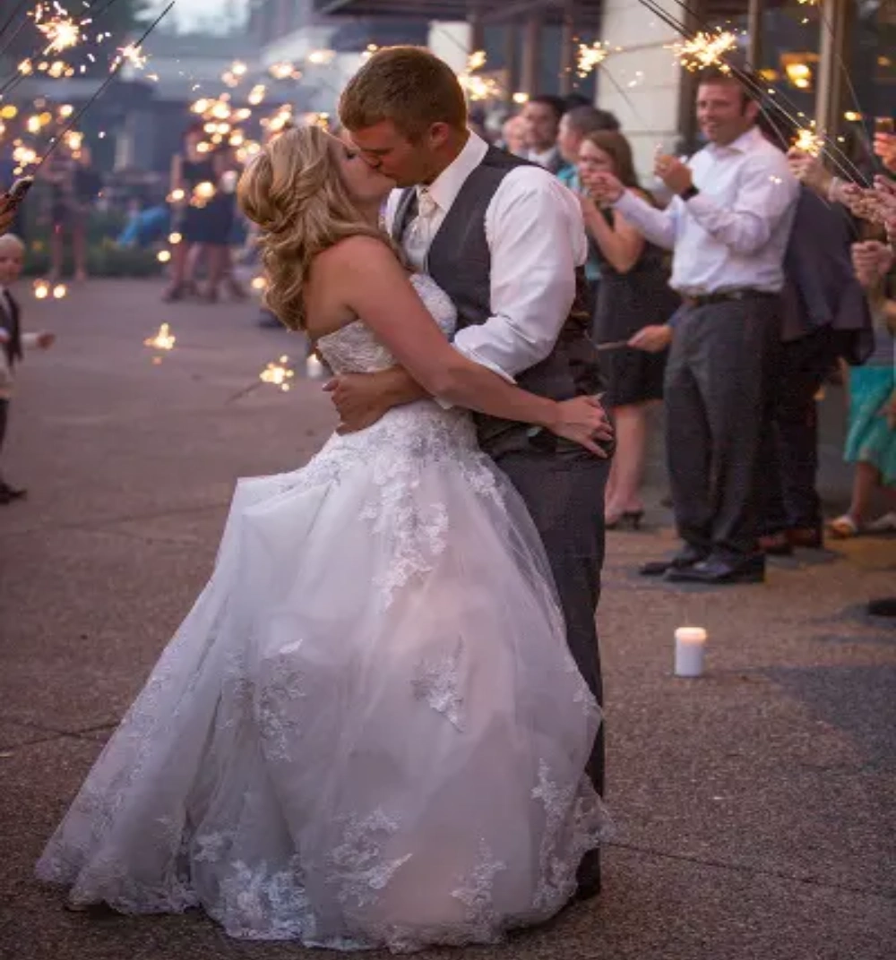 A bride and groom kissing in front of a crowd.