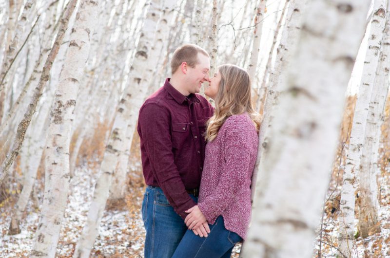 A man and woman kissing in the woods
