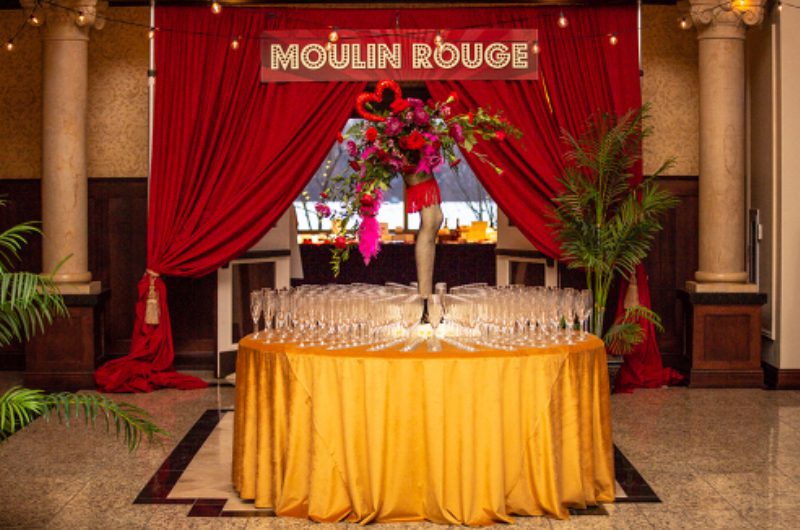 A table with champagne flutes and a red curtain.