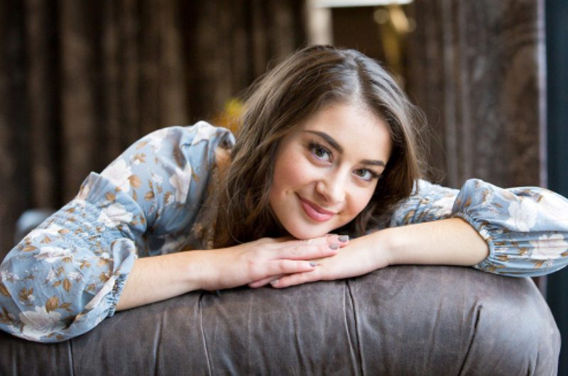 A woman leaning on the arm of a couch.