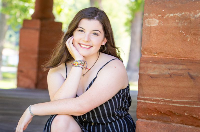 A woman sitting on the ground smiling for a picture.