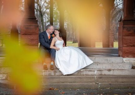 A man and woman sitting on steps in front of trees.